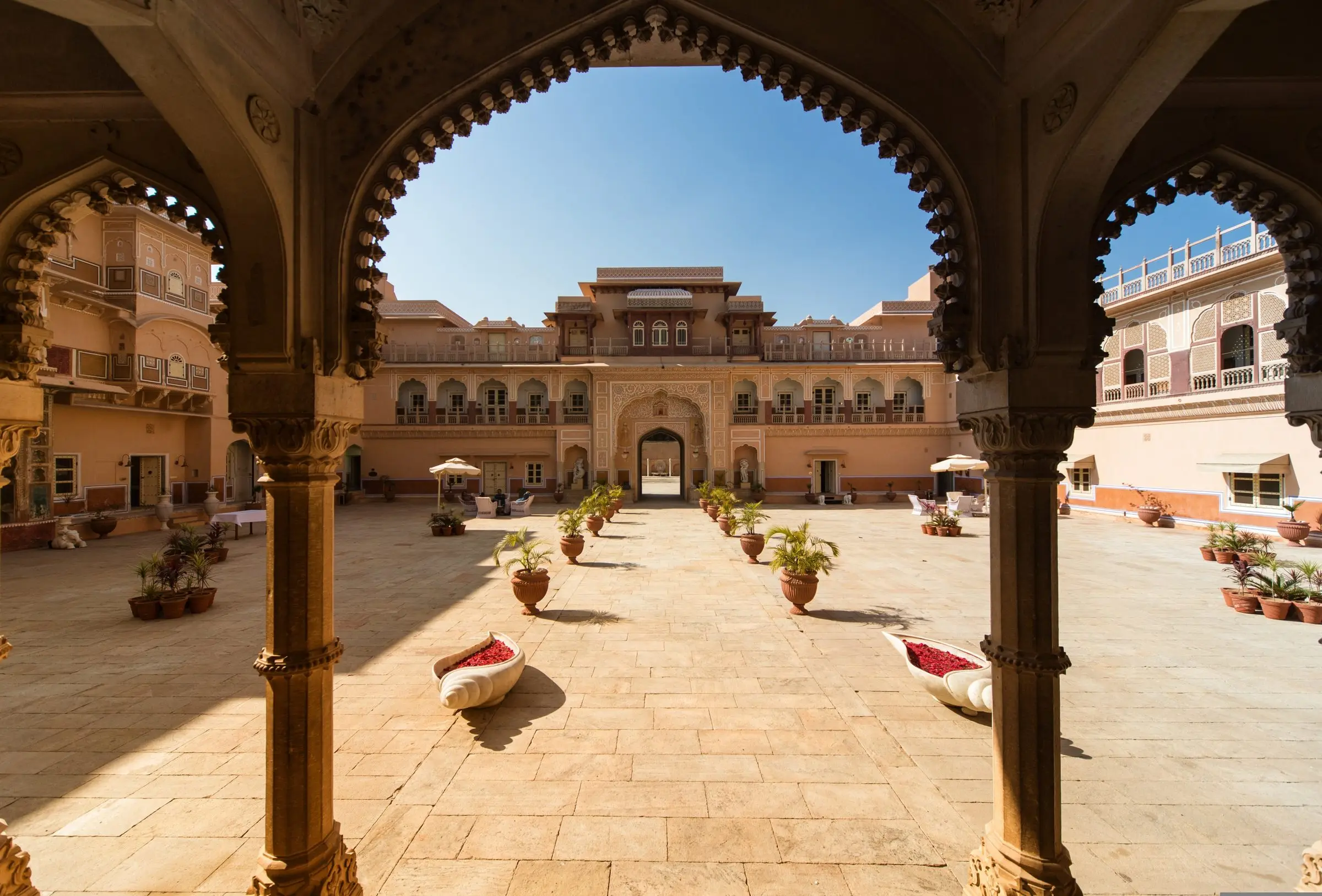 Carved arches opening onto the sunlit courtyard of Chomu Palace in Rajasthan