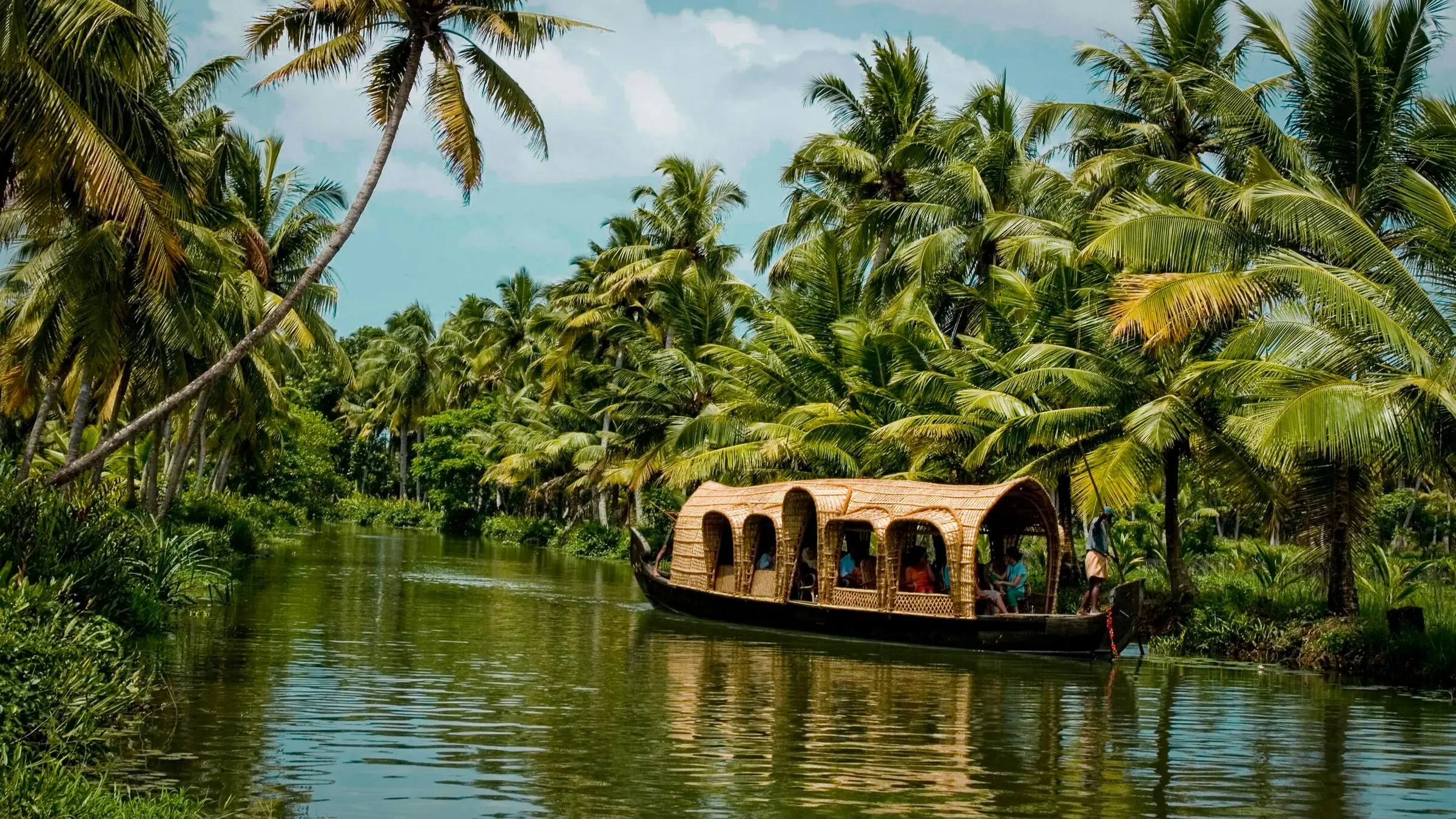 A traditional houseboat gliding through palm-lined Kerala backwaters